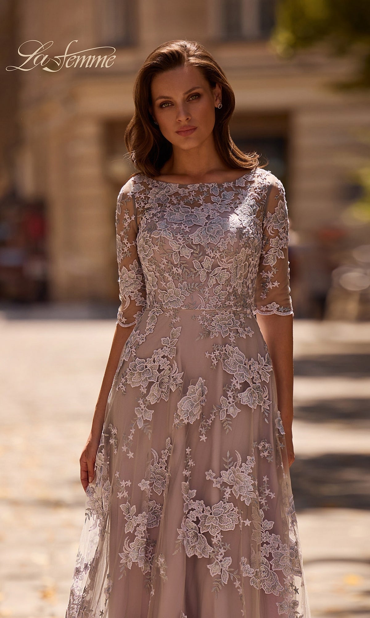 Woman wearing the Long Formal Dress: La Femme 27854 stands outdoors on a sunlit street, looking at the camera.
